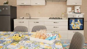 A modern kitchen with a dining table set for two, a refrigerator, a coffee machine, and a microwave. - Cannavacciuolo house (Gragnano)