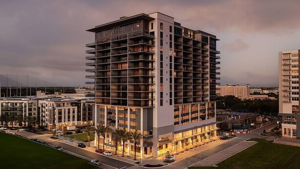 A high-rise hotel with multiple floors, balconies, and a well-lit facade. - Landing | Chic 2BD, Gym (St. Petersburg)