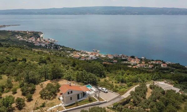 A coastal village with houses, a swimming pool, and a road leading to the sea. - Villa Maslina Nearby Split - Crovillas (Dugi Rat)