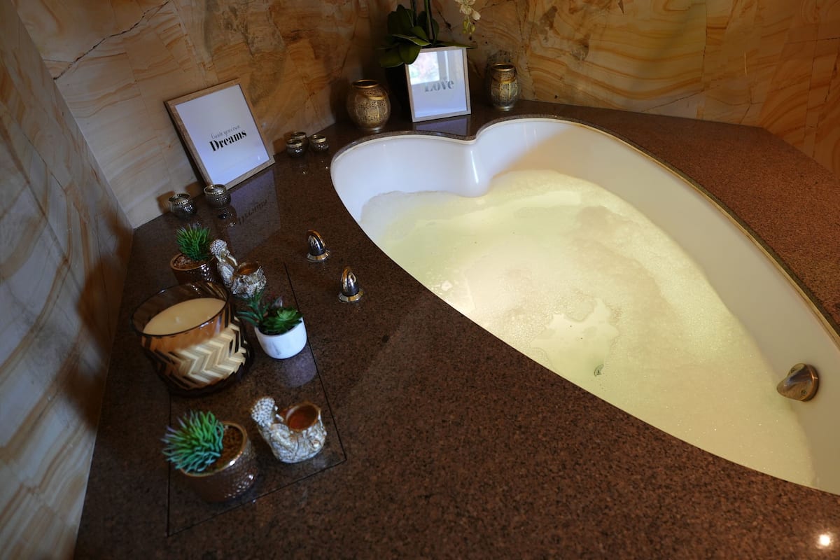 A bathroom with a freestanding bathtub, a marble countertop, and decorative items including a framed sign, a small potted plant, and a candle holder.