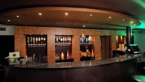 A bar area with multiple shelves of bottles and glasses, a cash register, and a green-lit ceiling. - Relax Gent Wellness (Lievegem)