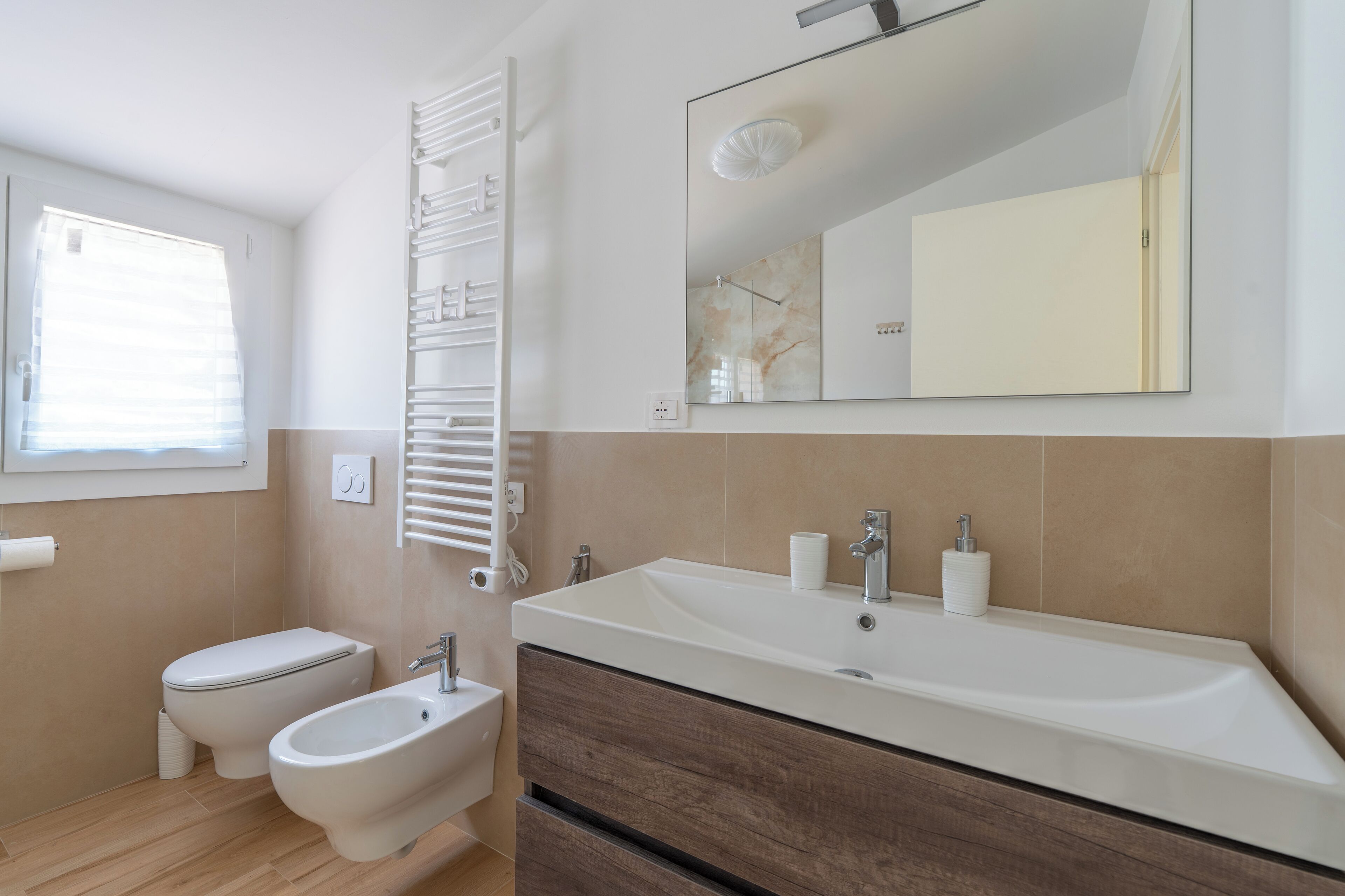 Une salle de bain moderne équipée de toilettes, d’un bidet et d’un grand lavabo avec un miroir au-dessus.
