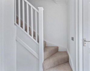 Un interior blanco con una escalera alfombrada y una puerta.