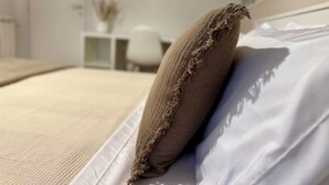 A bed with a white sheet and a brown pillow with frayed edges. - Domoi Property Apartment (Pisa)