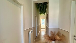 A hallway with a radiator, a hanging plant, and a decorative vase. - Domoi Property Apartment (Pisa)
