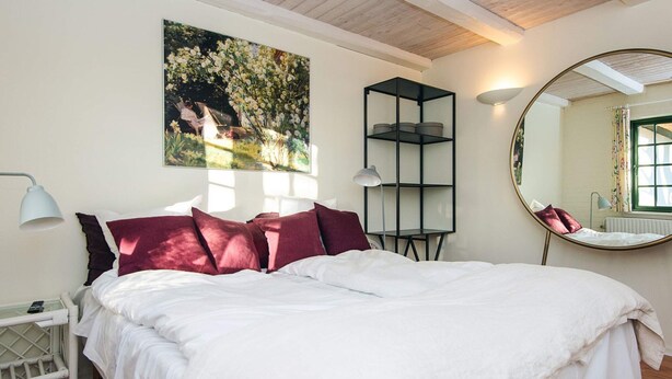A bedroom with a large bed, a bedside table, a lamp, a mirror, and a painting on the wall. - 2 Person Holiday Park Home in Fano (Fano)