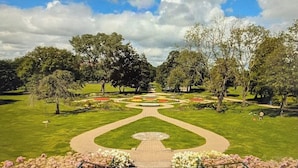 A formal garden with a central pathway, manicured lawns, and trees. - Perfect Riverside Home in Manchester, FREE Parking (Manchester)
