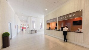 Un amplio vestíbulo de hotel con un mostrador de recepción identificado con las indicaciones “CAJERO” y “RECEPCIÓN”.