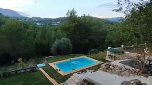 A swimming pool surrounded by a stone wall, with a view of a mountainous landscape. - Emelys (Kumluca)