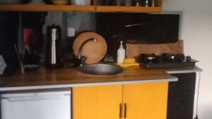 A compact kitchen with a yellow cabinet, a small refrigerator, and a stove. - Emelys (Kumluca)