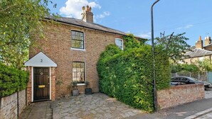 Une maison en briques avec le numéro « 2 » sur la porte, un petit jardin devant et une allée pavée.