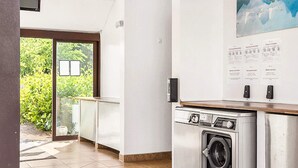Une cuisine moderne dotée d’un lave-linge et d’un sèche-linge intégrés, d’une porte vitrée donnant sur un jardin et d’un panneau d’affichage mural.