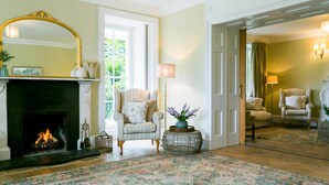 A room with a fireplace, a striped armchair, a floor lamp, and a patterned rug. - Treiorwerth -  a dog that sleeps 15 guests  in 7 bedrooms (Heart of Anglesey)