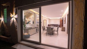 A modern interior with a dining area, kitchen, and a staircase leading to an upper level. - Cabo negro villa with large garden, swimming pool and barbecue area (Cabo Negro)