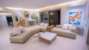 A modern living room with a sectional sofa, a coffee table, and a staircase leading to another level. - Cabo negro villa with large garden, swimming pool and barbecue area (Cabo Negro)