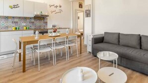 A modern living room with a grey sofa, a wooden dining table with chairs, and a small white coffee table.