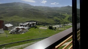 A view of a mountainous landscape with a building complex featuring multiple structures, a road, and a clear sky. - (3.4344) Appartement 60m2 sur les pistes 3 Vallées (Les Menuires)