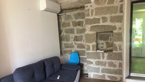 Ein Zimmer mit einer Steinswand, einem blauen Sessel und einem grauen Sofa.
