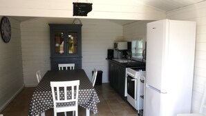 A compact kitchen with a dining table and chairs, a cabinet with glass doors, a refrigerator, and a stove. - Toucan, 25m² air-conditioned room on first floor, separate entrance (Les Ulmes)