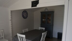 A dining area with a table set for four, white chairs, a clock on the wall, and a cabinet with glass doors. - Toucan, 25m² air-conditioned room on first floor, separate entrance (Les Ulmes)