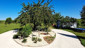 A residential driveway with a landscaped garden area, a small shed, and a tennis court. - Toucan, 25m² air-conditioned room on first floor, separate entrance (Les Ulmes)