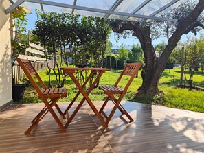 A wooden deck with a table and chairs, surrounded by a garden and a tree. - (The Little Place) House in Marina, Garden and Veranda (Marina di Massa)