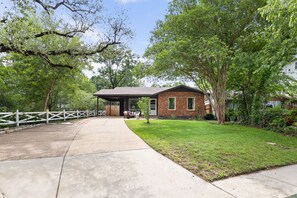 A residential house with a brick exterior, a covered porch, and a well-maintained lawn.