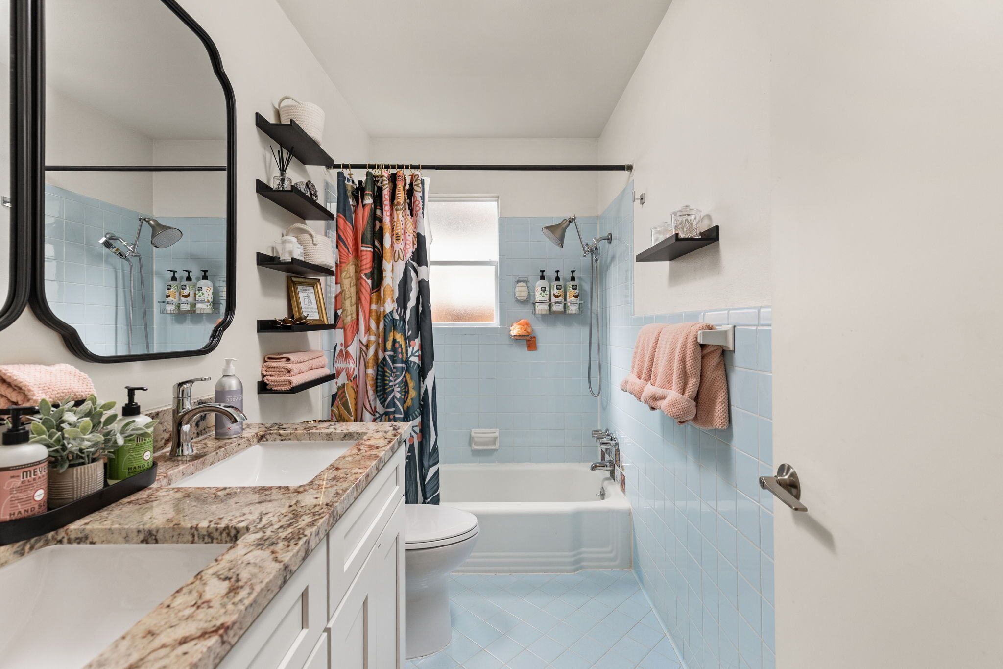 A bathroom with a white sink, a toilet, a bathtub, and a shower. There are shelves with toiletries and a mirror.
