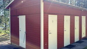 A row of four single-room cabins with white doors and a red exterior. - 5 Person Holiday Park Home in Vaxholm (Vaxholm)