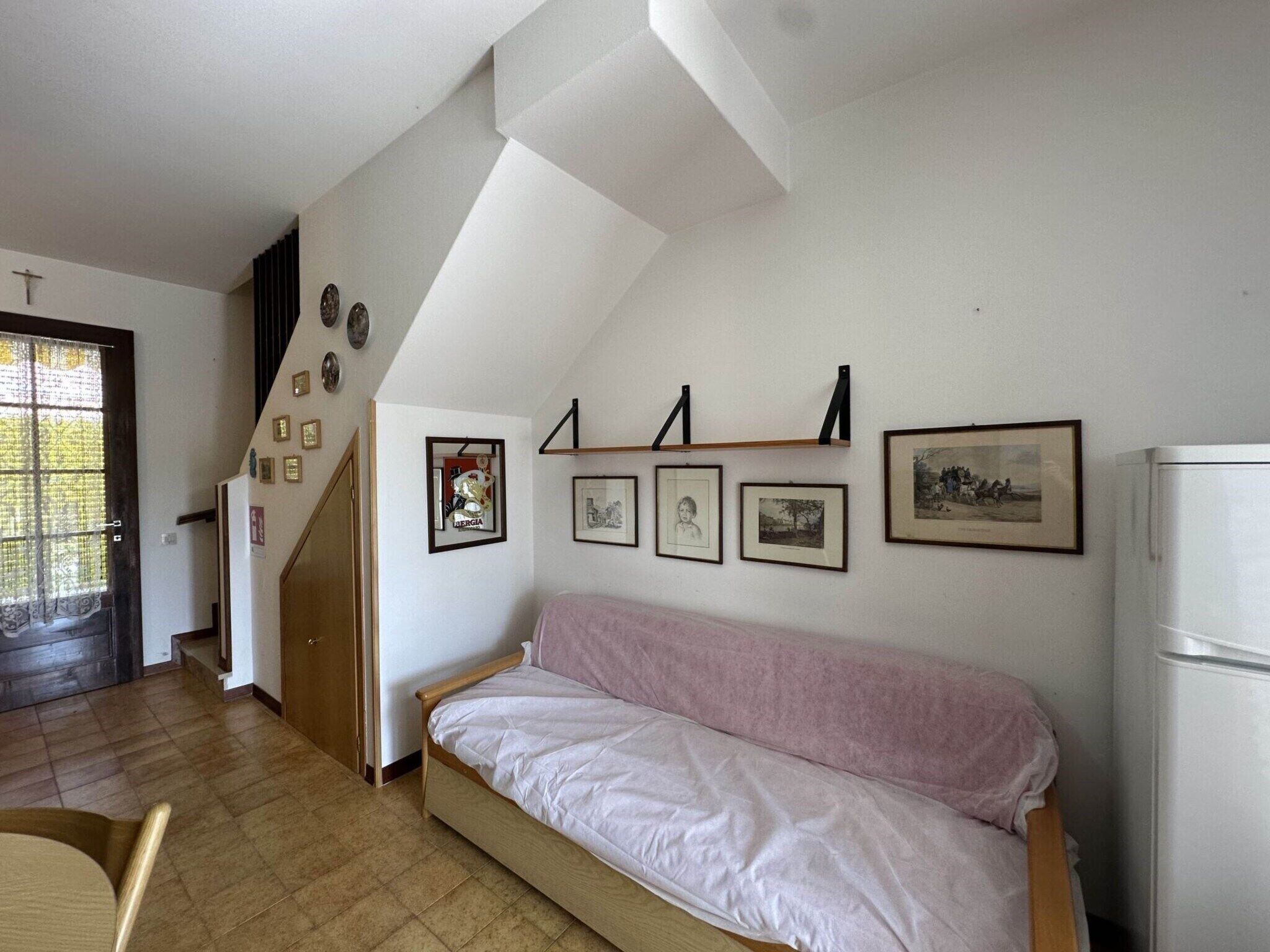Une pièce avec un lit en bois, un canapé blanc et un mur orné de tableaux encadrés.