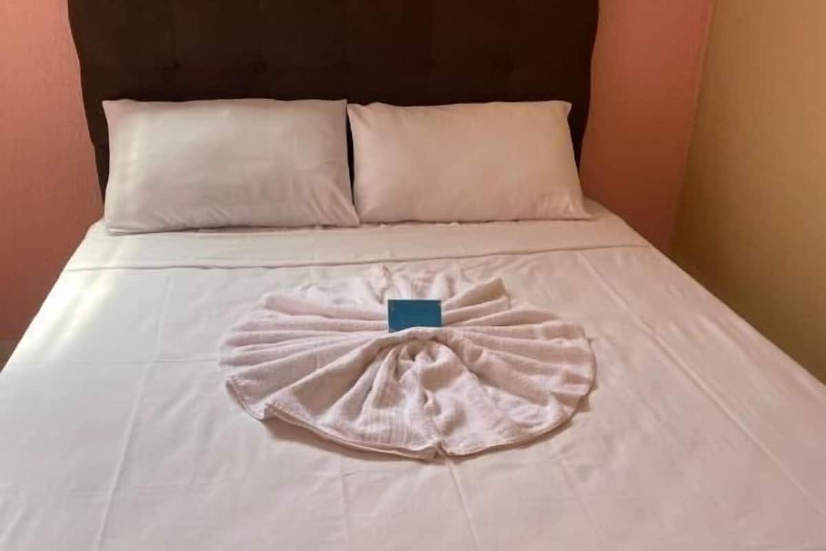 Une chambre d’hôtel avec un lit bien fait, une tête de lit et deux oreillers.
