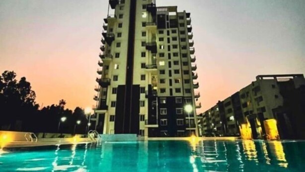 A high-rise building with a swimming pool at the base.