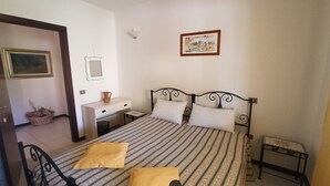 Une chambre à coucher comprenant un lit, une table de chevet, une chaise, un bureau et un tableau accroché au mur.