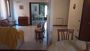 Une chambre d’hôtel comprenant un lit, une chaise en bois, une table à manger avec des chaises, un radiateur et une porte.