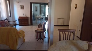 Ein Hotelzimmer mit Bett, einem Holzstuhl, einem Esstisch mit Stühlen, einem Heizkörper und einer Tür.