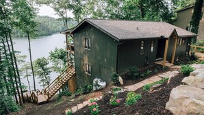 Une cabane avec un quai, entourée d’arbres et bordant un lac.
