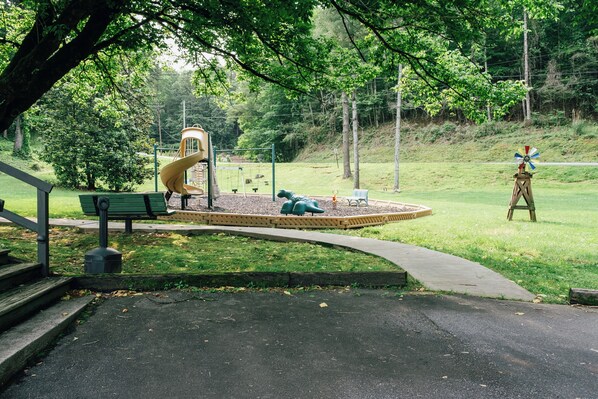 Un parque infantil con un tobogán, columpios y un molino.