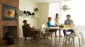 A dining area with a brick fireplace, modern chairs, and a dining table. - 4 Person Holiday Home on a Holiday Park in Romo (Rømø)