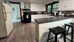 Una cocina moderna con armarios blancos, una estufa negra y encimera de granito.