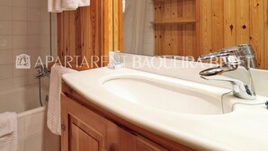 A bathroom with a wooden vanity, a white sink, and a mirror.
