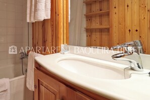 A bathroom with a wooden vanity, a white sink, and a mirror. - Floc - Edificio Mauberme (Baqueira)