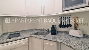 A kitchen with white cabinets, a granite countertop, a microwave, a toaster, and a dish rack.