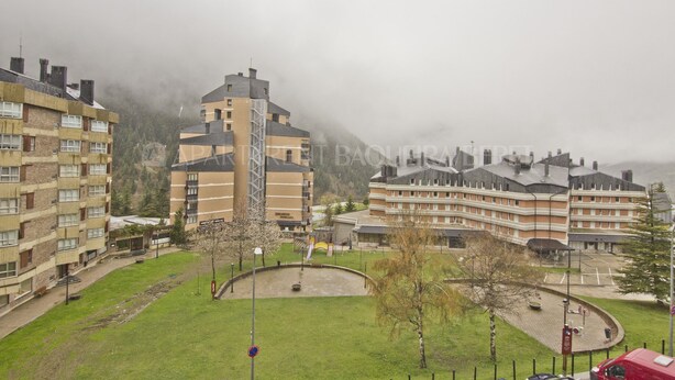 A multi-story hotel with a central courtyard, surrounded by buildings and a mountainous backdrop.