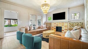 A modern living room with a beige sofa, teal armchairs, a coffee table, and a fireplace. - Hacienda Flamingo Unit 1 - Spacious Designer Flat with Sunroom & Style (West Palm Beach)
