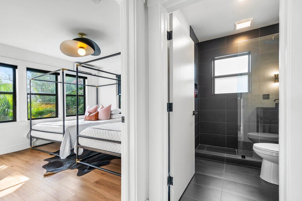 Ein modernes Schlafzimmer mit Etagenbett, großem Fenster und Blick ins Grüne sowie einem separaten Badezimmer mit Duschkabine.