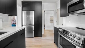 Une cuisine moderne équipée d’un réfrigérateur, d’un four et d’un four à micro-ondes en acier inoxydable.