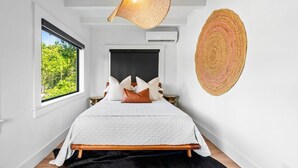 Une chambre à coucher comprenant un lit, une fenêtre, une décoration murale et un luminaire au plafond.