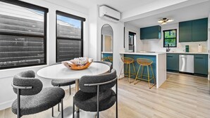 A modern kitchen with a central island, bar stools, and a dining area with a round table and chairs.