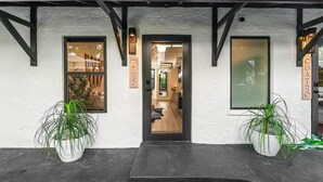 A building entrance with a black door, two potted plants, and a sign that reads "CUATRO".