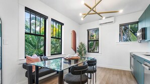 A modern kitchen with large windows, a glass dining table, and dark chairs.